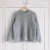 En septembergenser i grått, med ribbestrikket design, henger grasiøst på en trehenger mot en uberørt hvit garderobe.