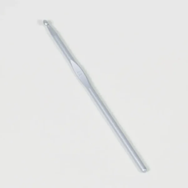 En heklenål i sølv med en glatt overflate og en liten krok i den ene enden er plassert på en vanlig hvit bakgrunn.