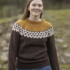 Kledd i "2309 Tema: 'Flokken' til hele familien" brun og sennepsmønstret genser sammen med blå jeans, rusler en person utendørs på en gresskledd sti, omfavner naturens rolige skjønnhet, og gjenspeiler varmen fra flokken.