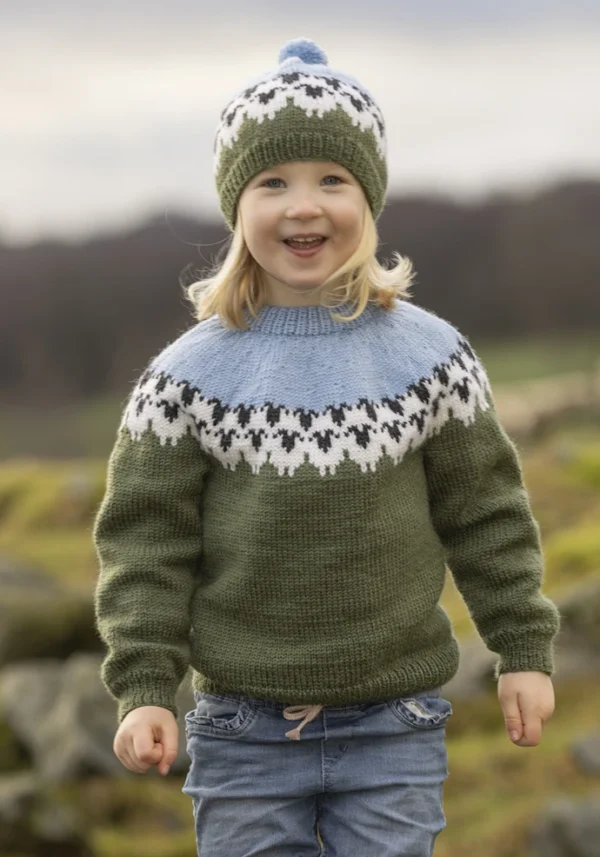 Et barn i strikket genser og matchende lue fra "Flokken"-kolleksjonen, med nordiske mønstre, står ute og stråler av glede, som om hver maske gjenspeiler familiens lykke.