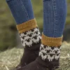 En person iført mønstrede, strikkede sokker og blå jeans står på en høyballe og fanger essensen av 2309 Tema: "Flokken" til hele familien.