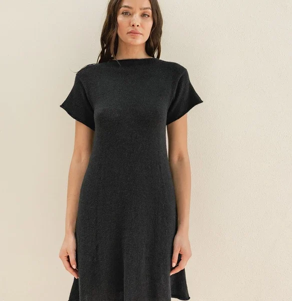 Iført en trendy 2504-07 Milly-kjole med korte ermer, står en person mot en ensfarget beige bakgrunn.