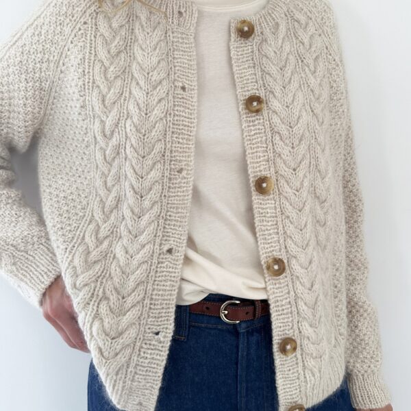Noen har på seg Siri Cardigan i kremfarget med brune knapper, over en hvit t-skjorte og sammen med blå jeans.